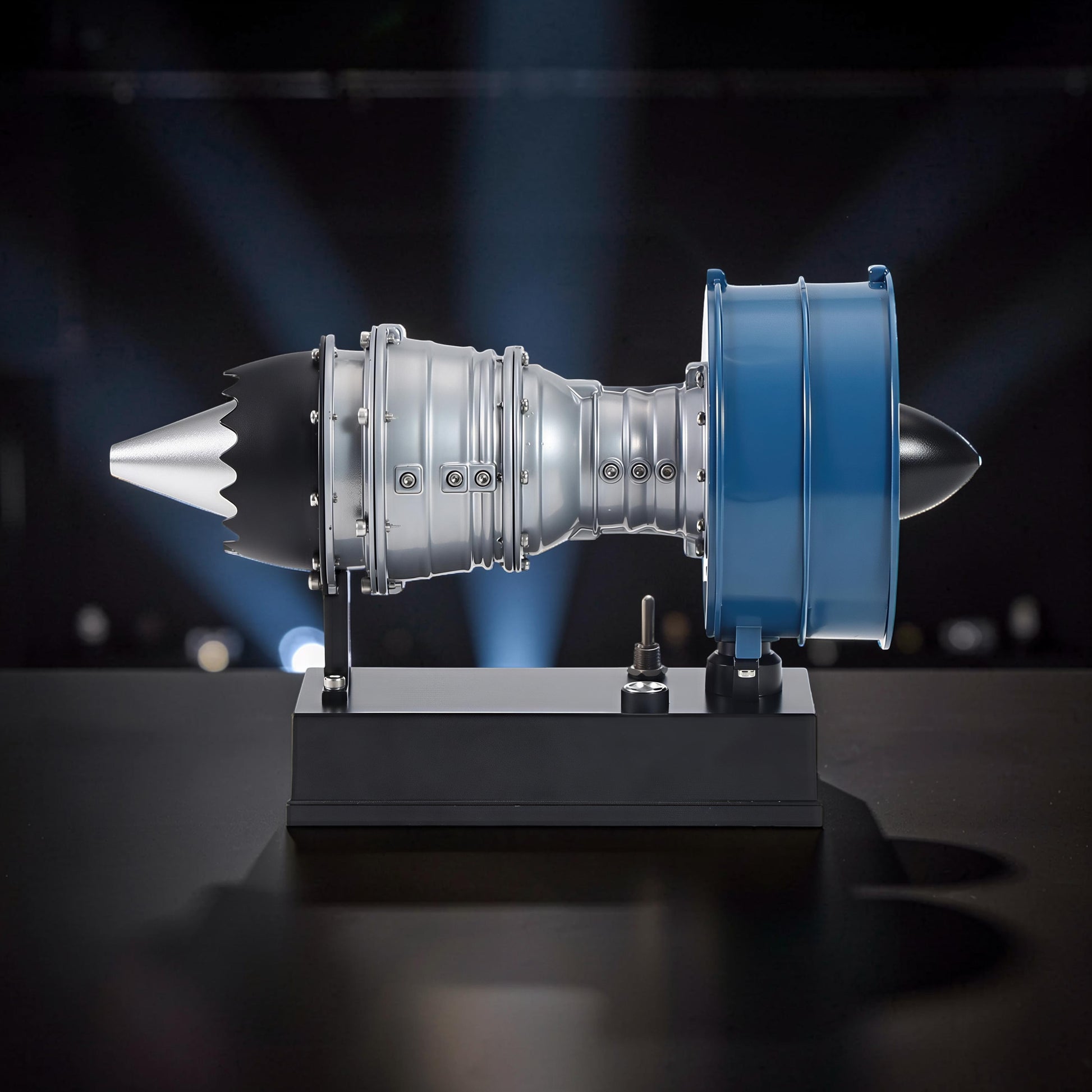 The Curious Mind Mini Turbofan Engine DIY Kit, a detailed model with silver, black, and blue PLA components on a black display stand.