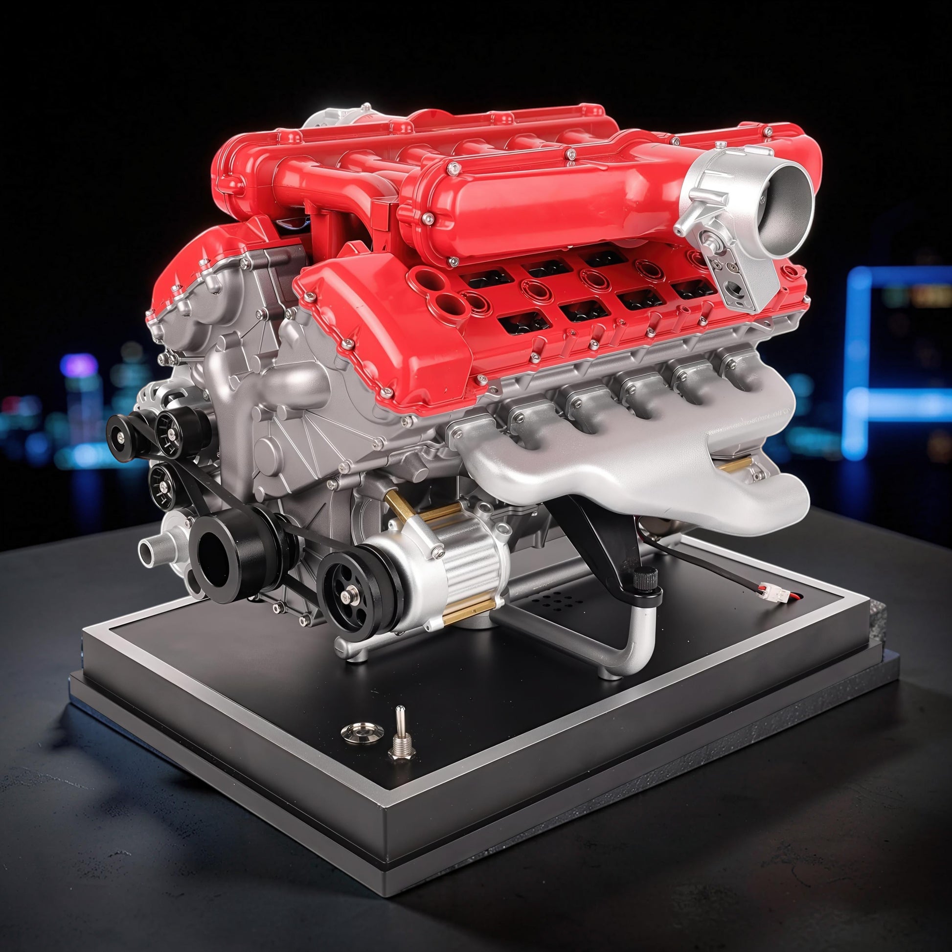 The Curious Mind V12 car engine DIY kit, a detailed metal model with red and silver components on a black display base.