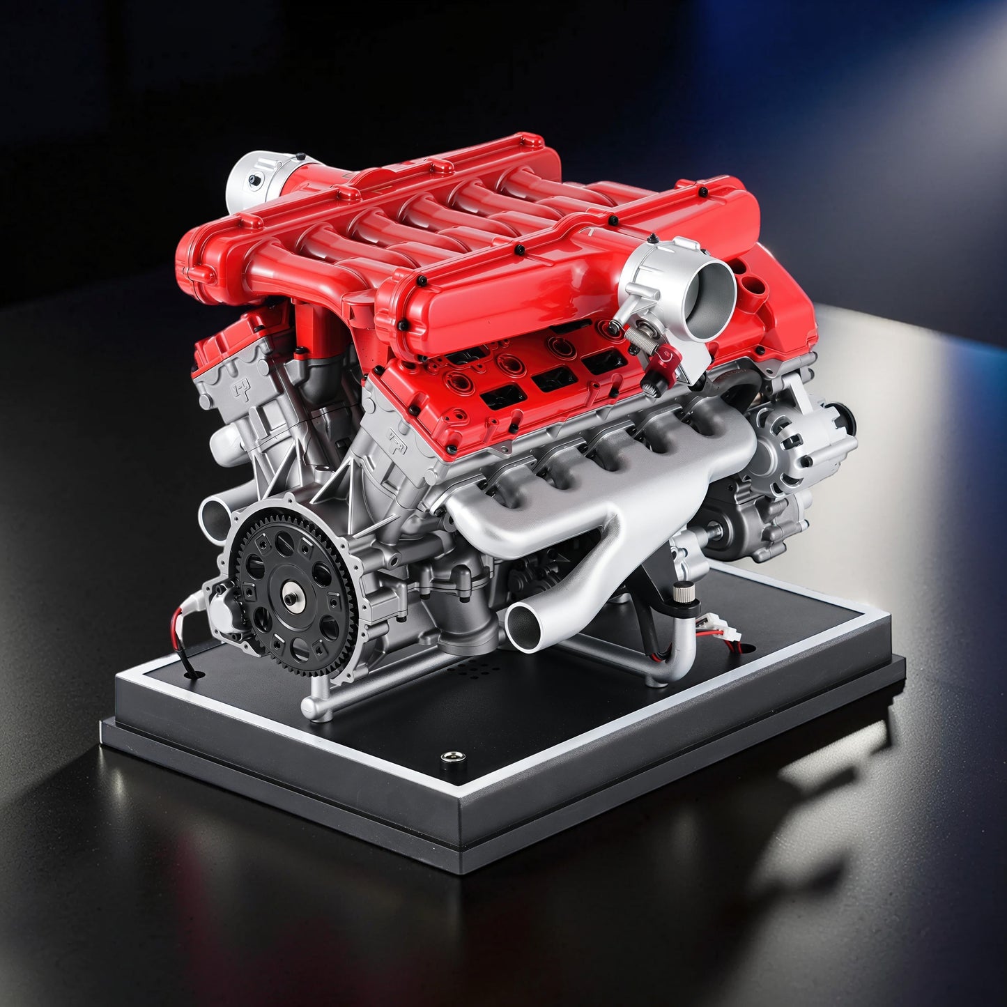 The Curious Mind V12 car engine DIY kit, a detailed metal model with red and silver components on a black display base.
