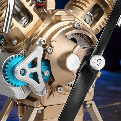 The Curious Mind Mini V2 Double-Cylinder Engine DIY Kit, a detailed metal mechanical model with gold and silver finishes, blue gears, and a black propeller.