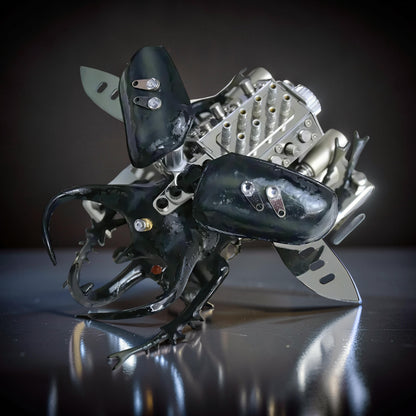 The Curious Mind Mechanical V8 Beetle Display Model, a collector's engine display crafted from polished metal and black components, resembling a rhinoceros beetle.