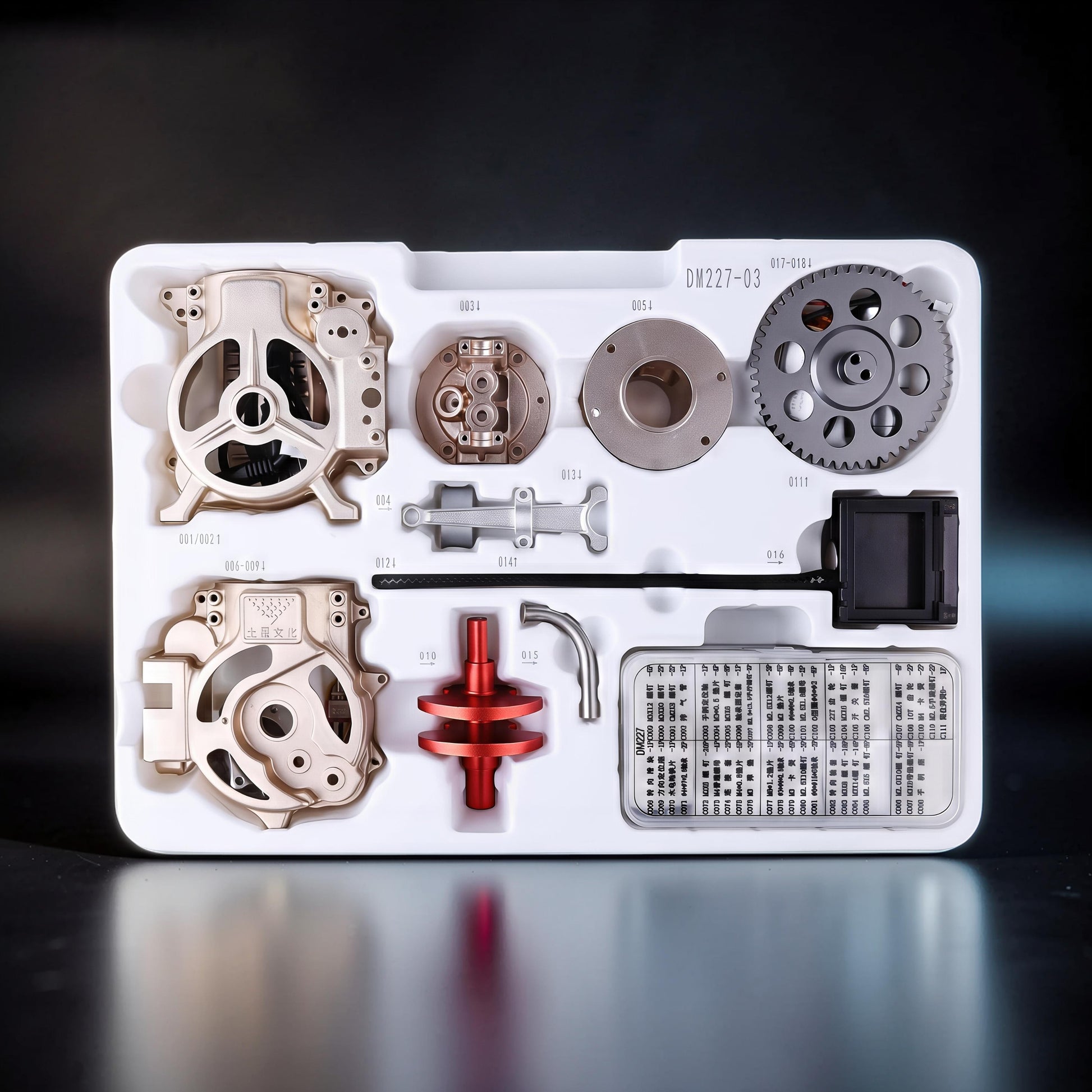 The Curious Mind Vintage Classic Car DIY Kit metal mechanical model parts laid out in a white tray. Includes gears, engine components, and instructions.