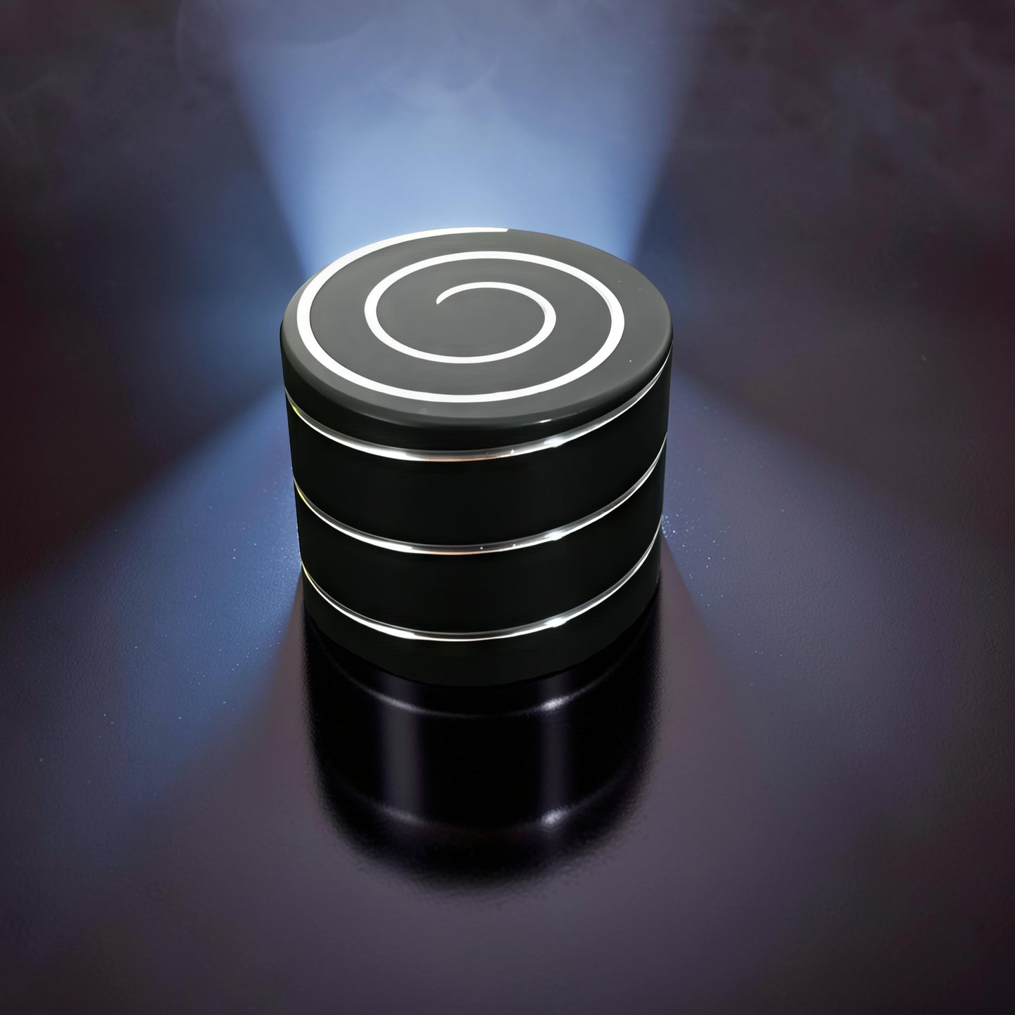 The Curious Mind Vortecon kinetic desk spinner in black metal with a silver spiral design on top. Weighted for smooth motion.