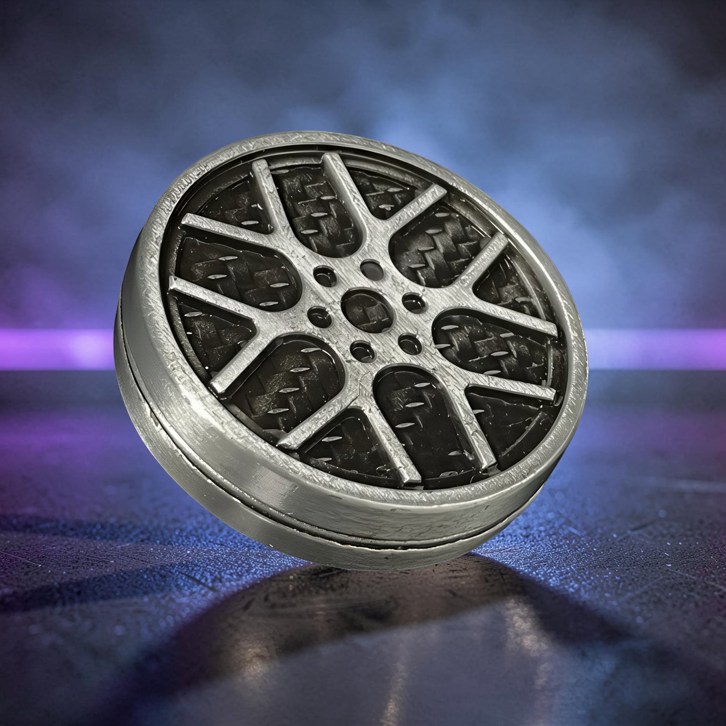 The Curious Mind Wheel Hub Coin Clicker fidget toy, silver metal with a car wheel design and carbon fiber texture.