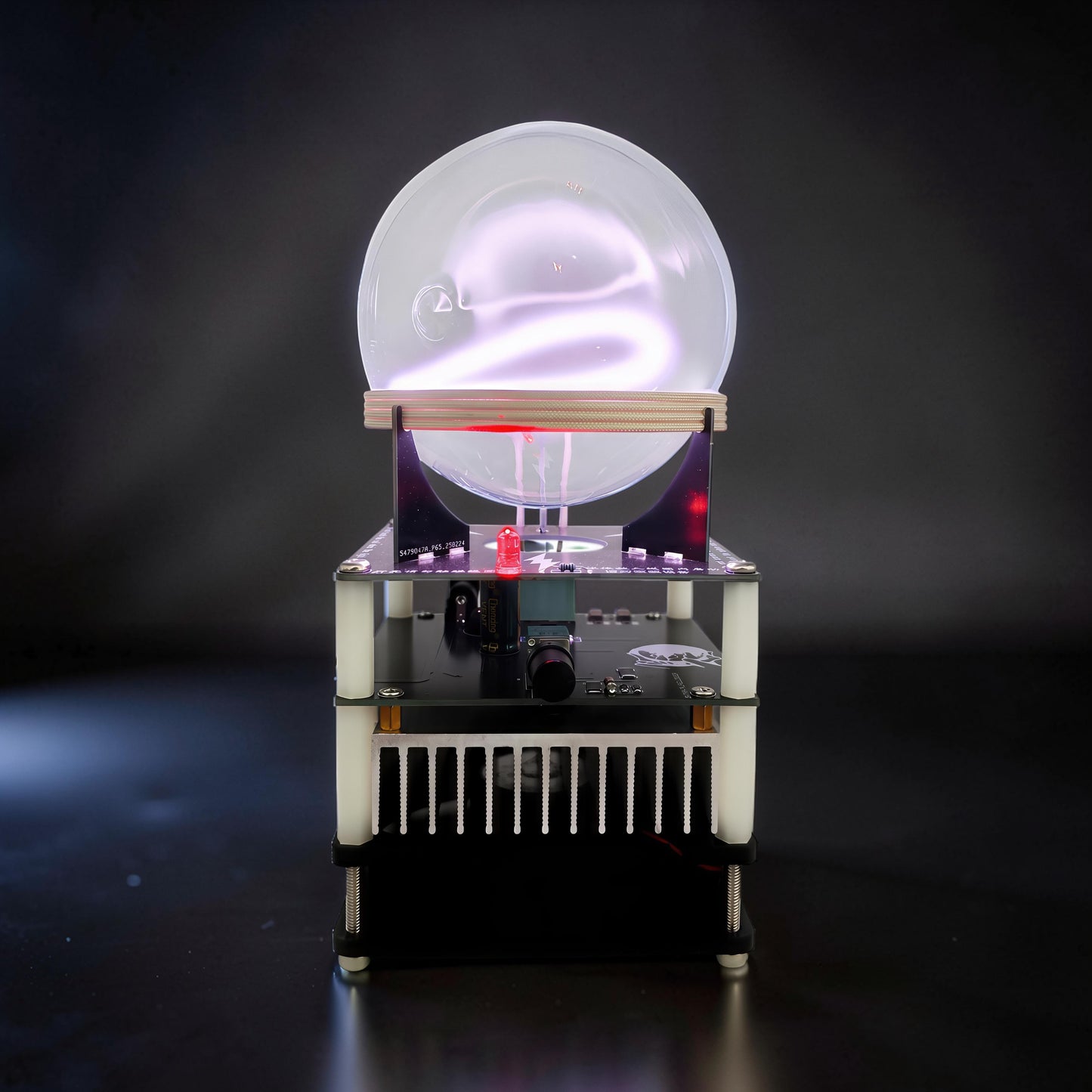 The Curious Mind Xenon Ion Ring Glass Sphere interactive science display with glowing purple plasma inside a clear glass orb on a black base with electronic components.