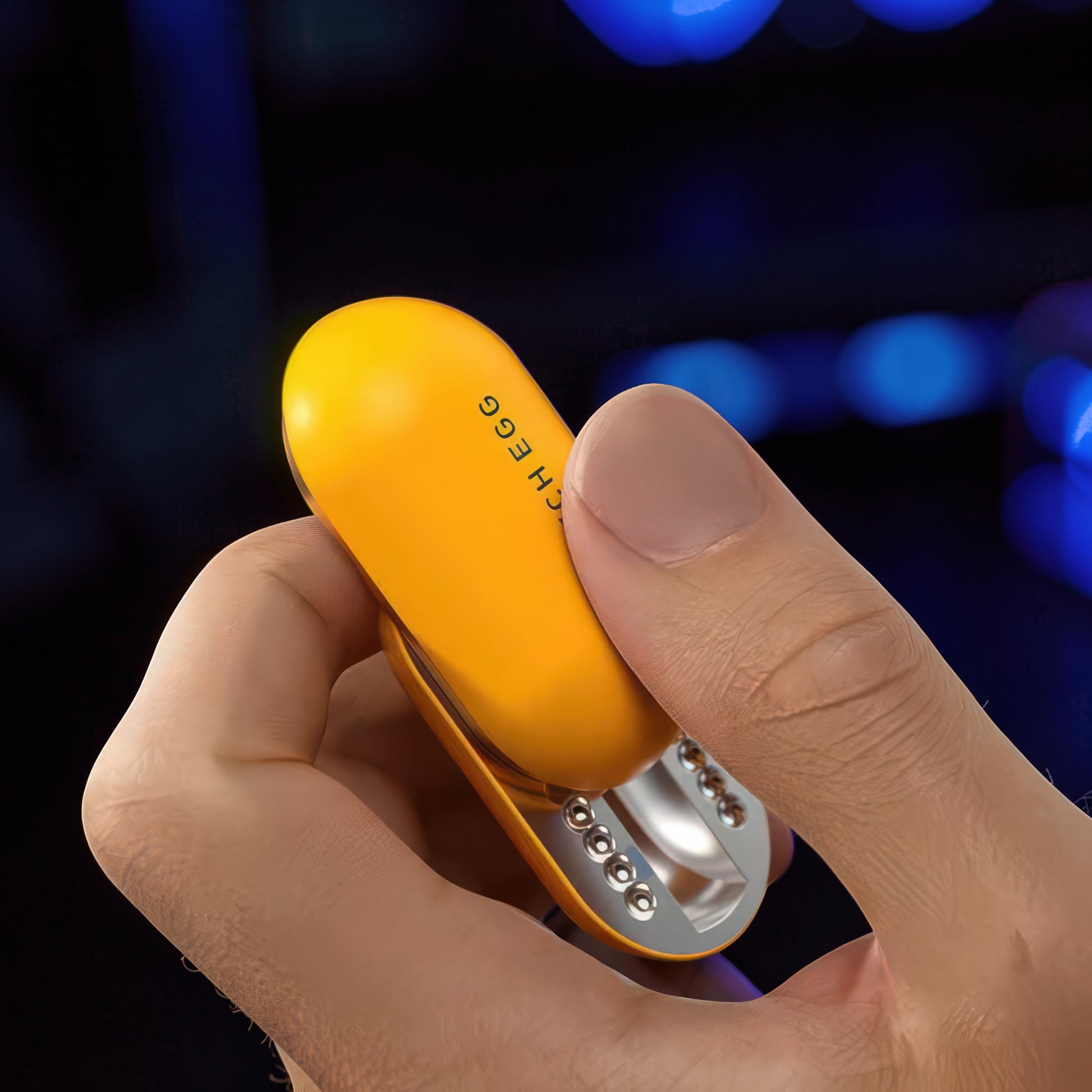 The Curious Mind Mech Egg Clicker Slider, a yellow metal fidget toy with a capsule shape, held in a hand.